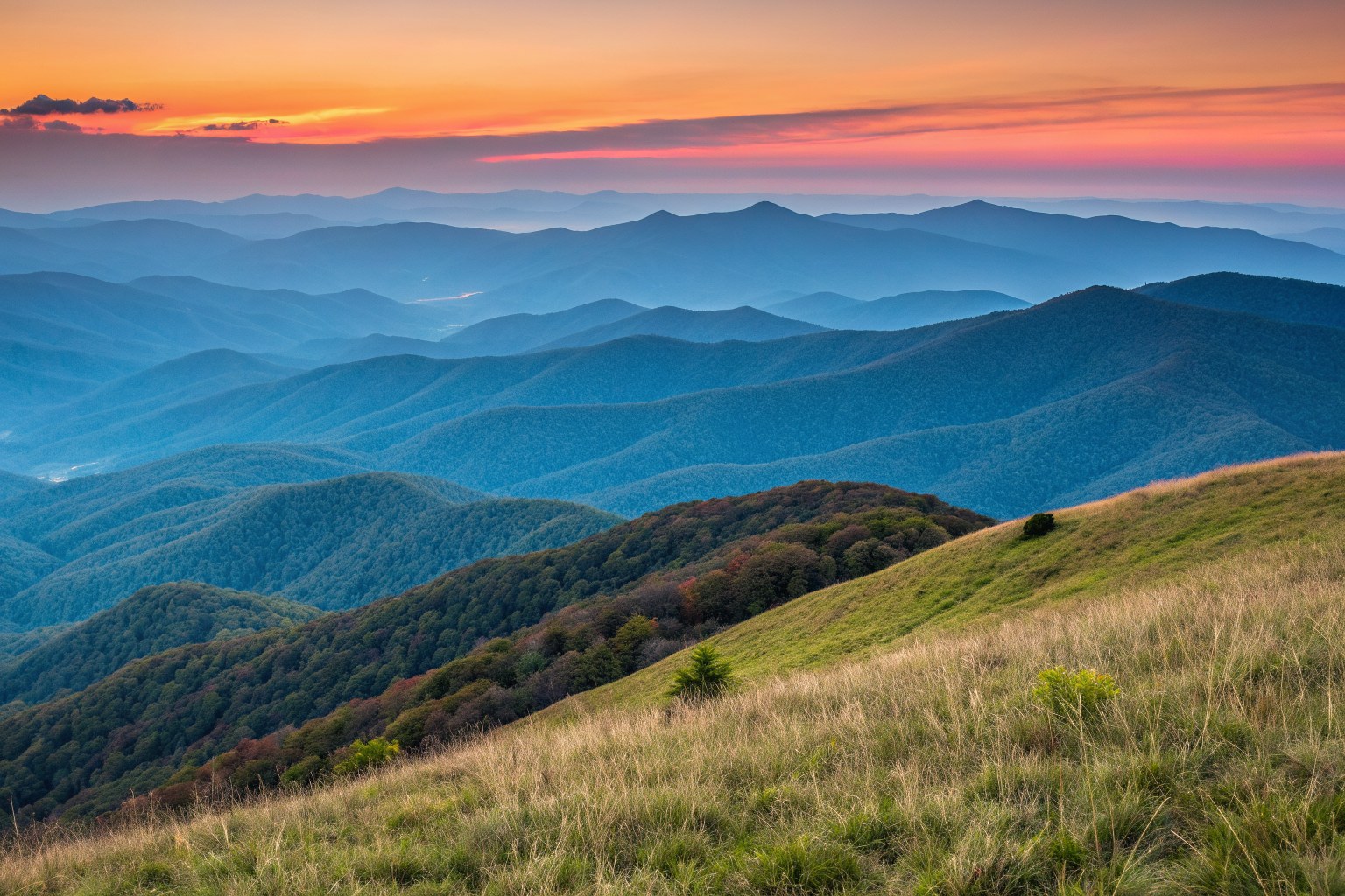 Layers of blue mountain ridges under an orange sunset sky